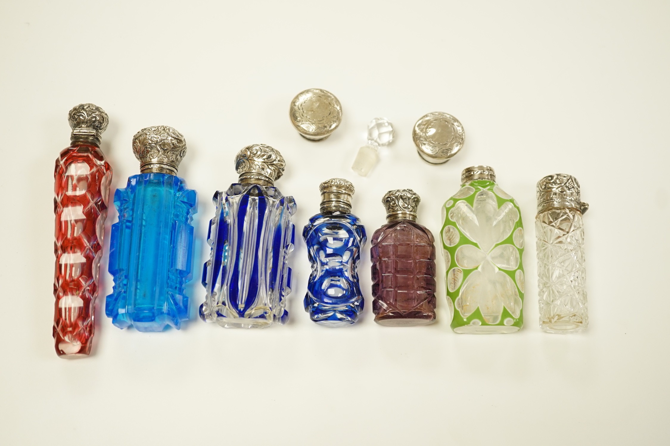 A late Victorian silver mounted cut glass scent bottle, Charles Boyton II, London, 1896, 82mm and six other late 19th/early 20th century, silver or white metal mounted coloured cut glass scent bottles (some a.f.) and two